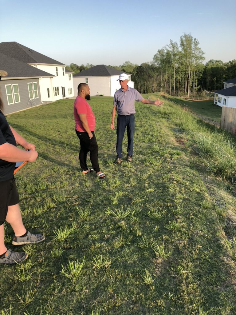 CertaShed team member Adam consulting with a client on a sloped backyard lot in Greenville SC
