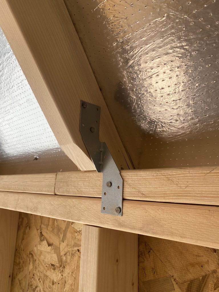 Heavy duty steel hurricane ties securing roof rafters to wall plates for structural integrity